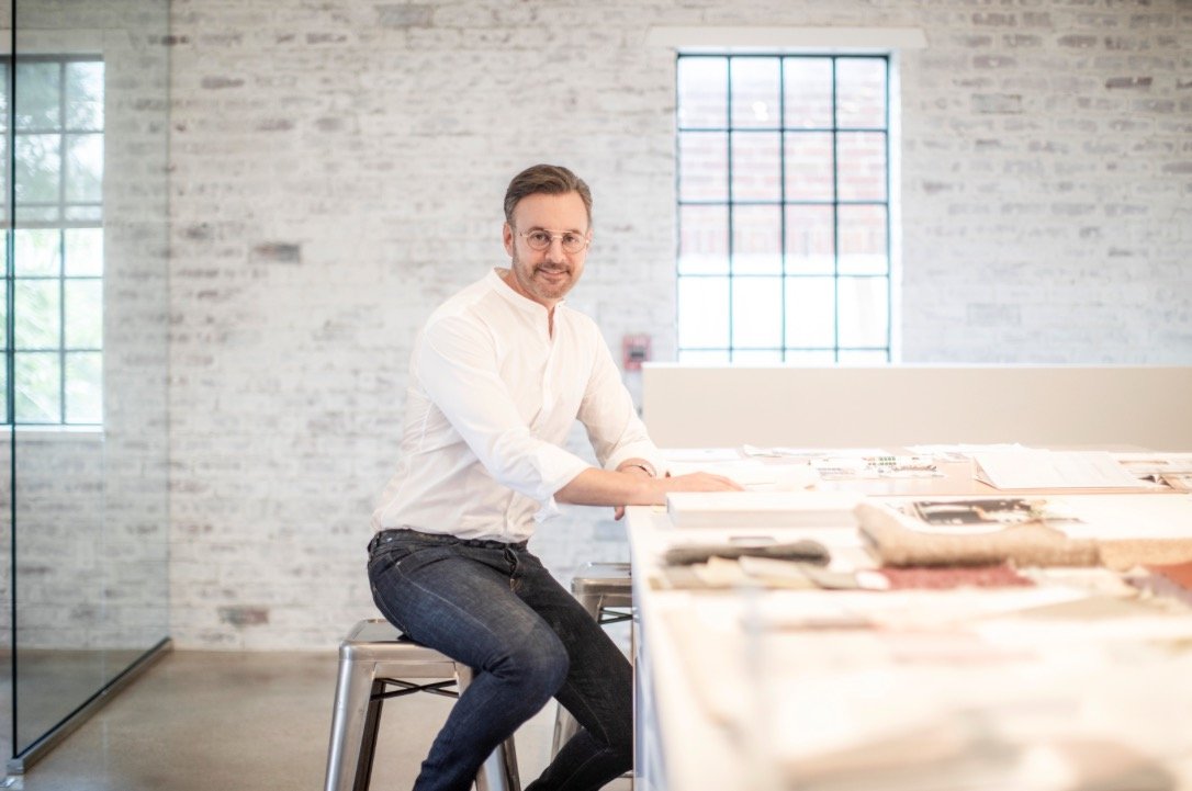 Kevin Spearman, principal designer, seated at a large worktable reviewing materials in his whitewashed brick Houston studio