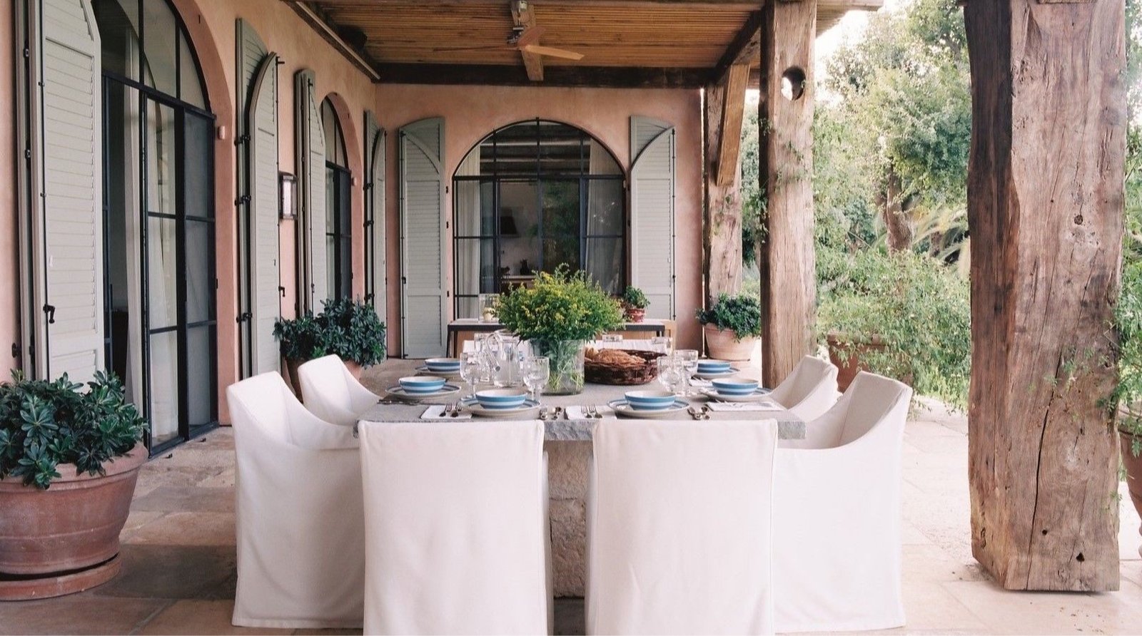 Covered terrace with arched steel doors and a long dining table at a Tuscan influenced estate near Tel Aviv